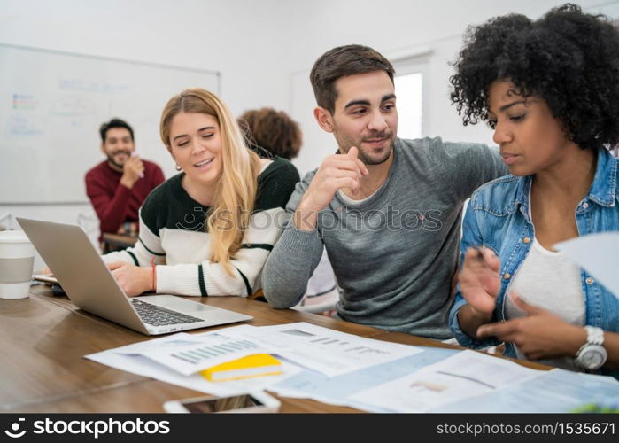 Young creative designers working in a project and discussing new order development on workplace. Business and team work concept.