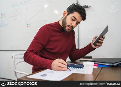 Young creative man working with his digital tablet on his workplace. Business concept.