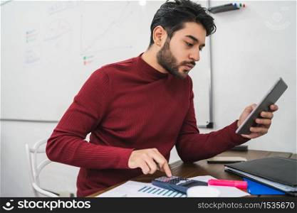 Young creative man working with his digital tablet on his workplace. Business concept.