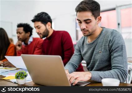 Young creative man working with his laptop on his workplace. Business concept.
