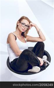 Young creative woman sitting on the modern chair on white background. Young creative woman
