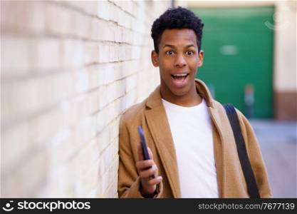 Young Cuban man with a surprised look on his face in the street. Black guy smiling in urban background.. Young black man with a surprised look on his face in the street.