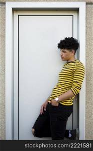 young curly hispanic man leaning door casing
