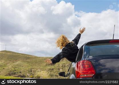 young curly woman leaning out car window