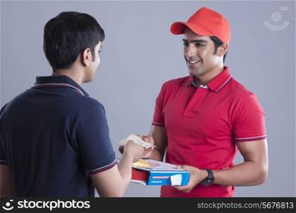 Young customer paying pizza delivery man over gray background