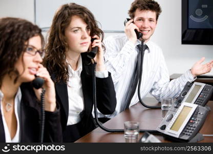 Young customer service operator team working at office, holding phone, calling, giving helpdesk support.