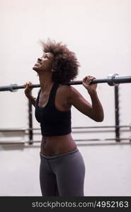 Young Cute african american sport woman in fitness room lifting empty bar