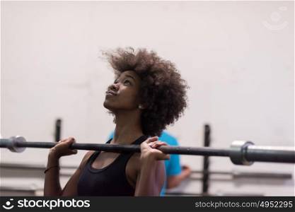 Young Cute african american sport woman in fitness room lifting empty bar