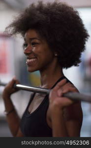 Young Cute african american sport woman in fitness room lifting empty bar