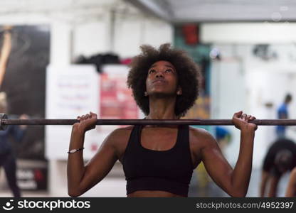 Young Cute african american sport woman in fitness room lifting empty bar