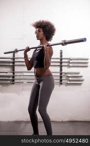 Young Cute african american sport woman in fitness room lifting empty bar