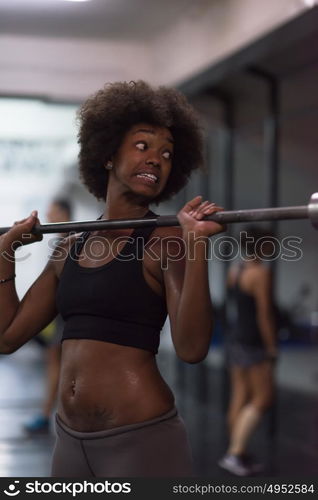 Young Cute african american sport woman in fitness room lifting empty bar