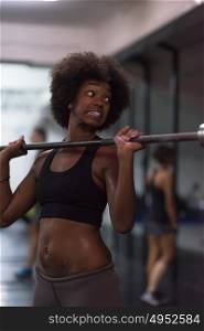 Young Cute african american sport woman in fitness room lifting empty bar