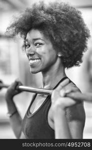 Young Cute african american sport woman in fitness room lifting empty bar