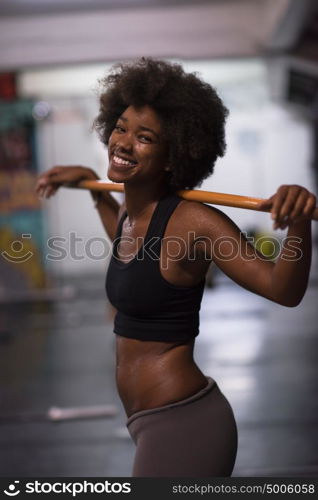 Young Cute african american sport woman in fitness room lifting empty bar