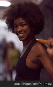 Young Cute african american sport woman in fitness room lifting empty bar