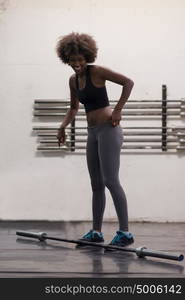 Young Cute african american sport woman in fitness room lifting empty bar