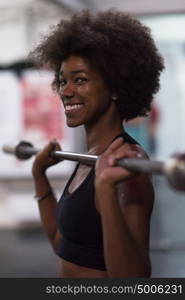 Young Cute african american sport woman in fitness room lifting empty bar