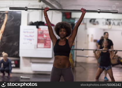 Young Cute african american sport woman in fitness room lifting empty bar