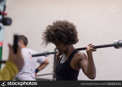 Young Cute african american sport woman in fitness room lifting empty bar