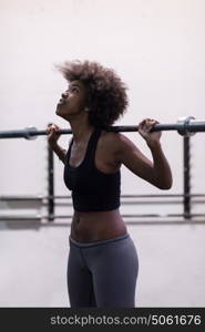 Young Cute african american sport woman in fitness room lifting empty bar