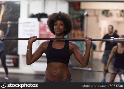 Young Cute african american sport woman in fitness room lifting empty bar