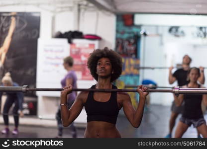 Young Cute african american sport woman in fitness room lifting empty bar