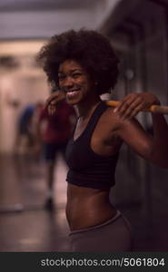 Young Cute african american sport woman in fitness room lifting empty bar