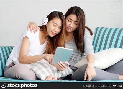 Young cute asia lesbian couple using tablet with happiness at home, lgbt, homosexual, lesbian couple lifestyle