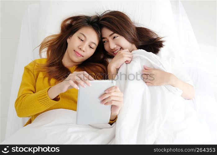 Young cute asia lesbian couple using tablet with happiness on white bed, lgbt, homosexual, lesbian couple lifestyle