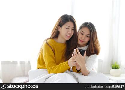 Young cute asian lesbian couple using smart phone with happiness at home, lgbt, homosexual, lesbian couple lifestyle