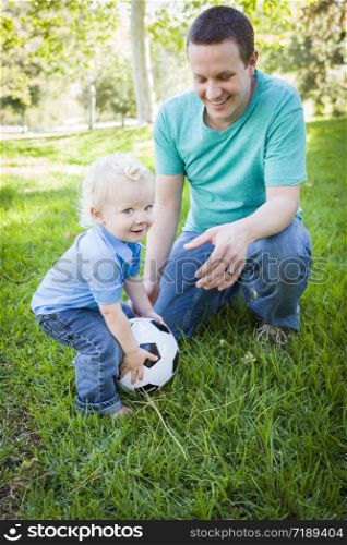Young Cute Boy and Dad Playing with Soccer Ball in the Park.