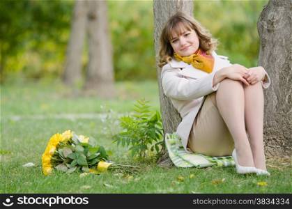 Young cute girl with a bouquet of yellow roses in autumn cool weather