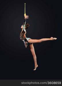 Young cute woman in gymnast suit show athletic skill on black background