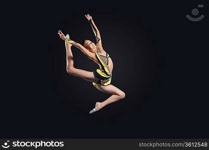 Young cute woman in gymnast suit show athletic skill on black background