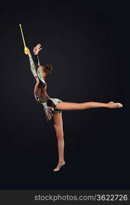 Young cute woman in gymnast suit show athletic skill on black background