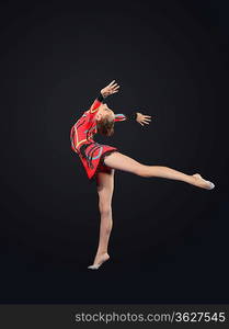 Young cute woman in gymnast suit show athletic skill on black background