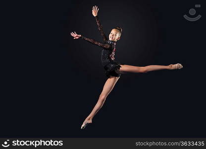 Young cute woman in gymnast suit show athletic skill on black background