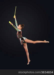 Young cute woman in gymnast suit show athletic skill on black background