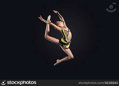 Young cute woman in gymnast suit show athletic skill on black background