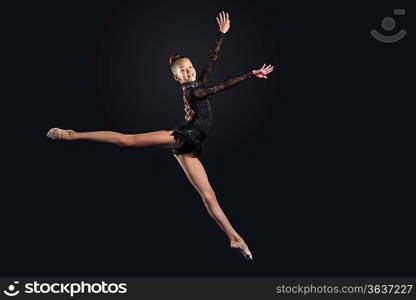 Young cute woman in gymnast suit show athletic skill on black background