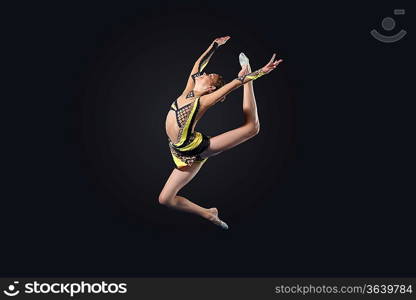 Young cute woman in gymnast suit show athletic skill on black background