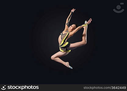 Young cute woman in gymnast suit show athletic skill on black background