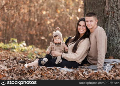 young dad and mom with baby girl relaxing on blanket in autumn park on sunny day. happy family concept. mother&rsquo;s, father&rsquo;s, baby&rsquo;s day. young dad and mom with baby girl relaxing on blanket in autumn park on sunny day. happy family concept. mother&rsquo;s, father&rsquo;s, baby&rsquo;s day.