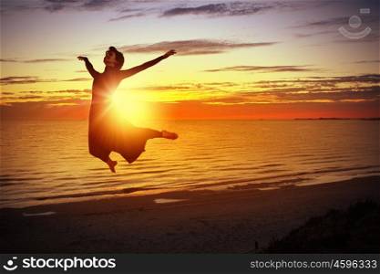 Young dancer. Silhouette of dancer jumping against city in lights of sunrise
