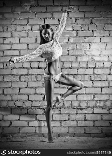 Young dancing woman on grey brick wall (monochrome version)