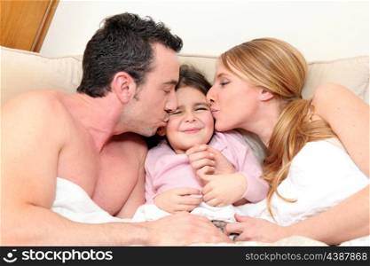 Young daughter in bed with parents