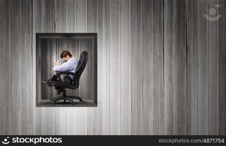 Young depressed businessman sitting in chair isolated from world. Leave me alone