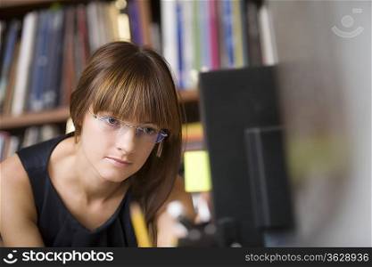 Young designer leans forward working at computer screen