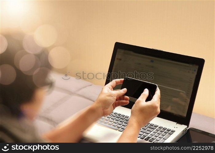  young designer working with blank screen smart phone and computer in bed as concept